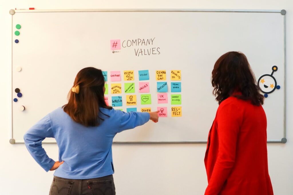 employee showing sticky note with ideas on a whiteboard with company values