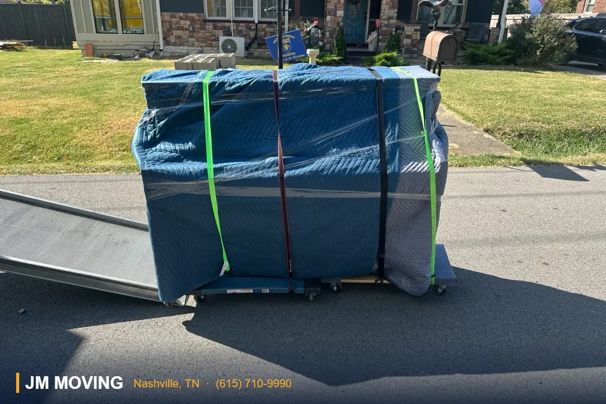 Nashville movers - Fully blanket-protected piano secured on a dolly near a loading ramp